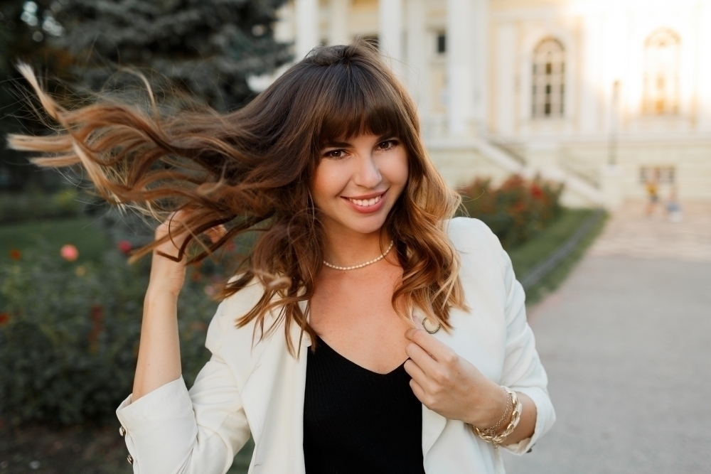 blissful laughing woman playing with hairs enjoing uotumn day european city elegant look
